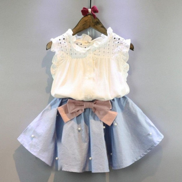 Blusa blanco con pollera celeste con detalles de perlas y moño