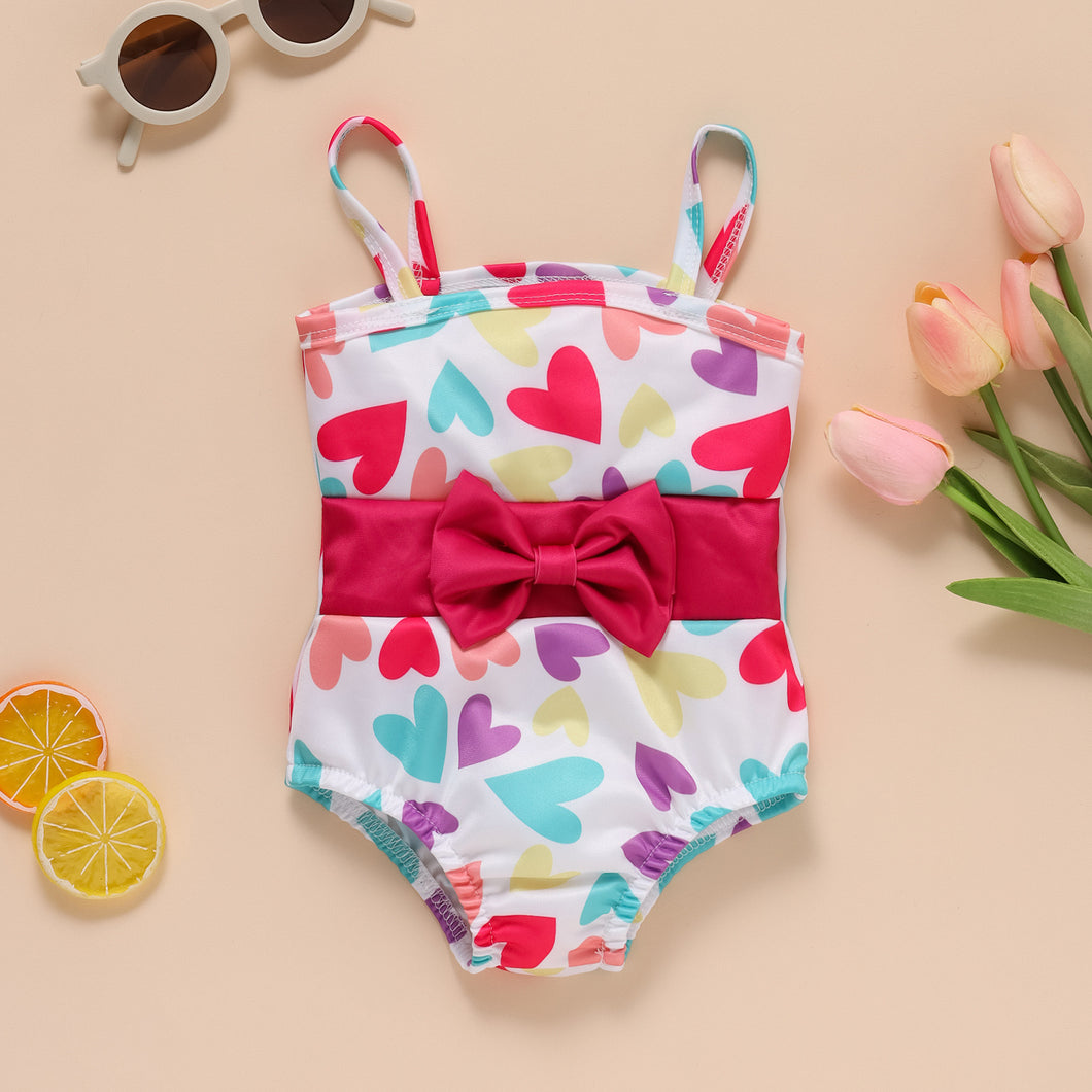 Traje de baño blanco con estampas de corazones coloridos y moño