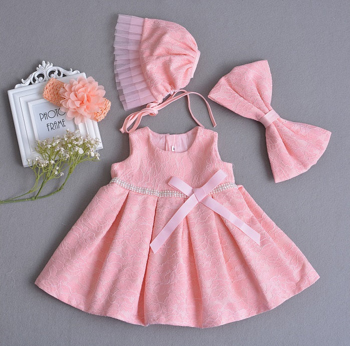 Vestido rosa de encaje con perlas en la cintura, moño y gorra